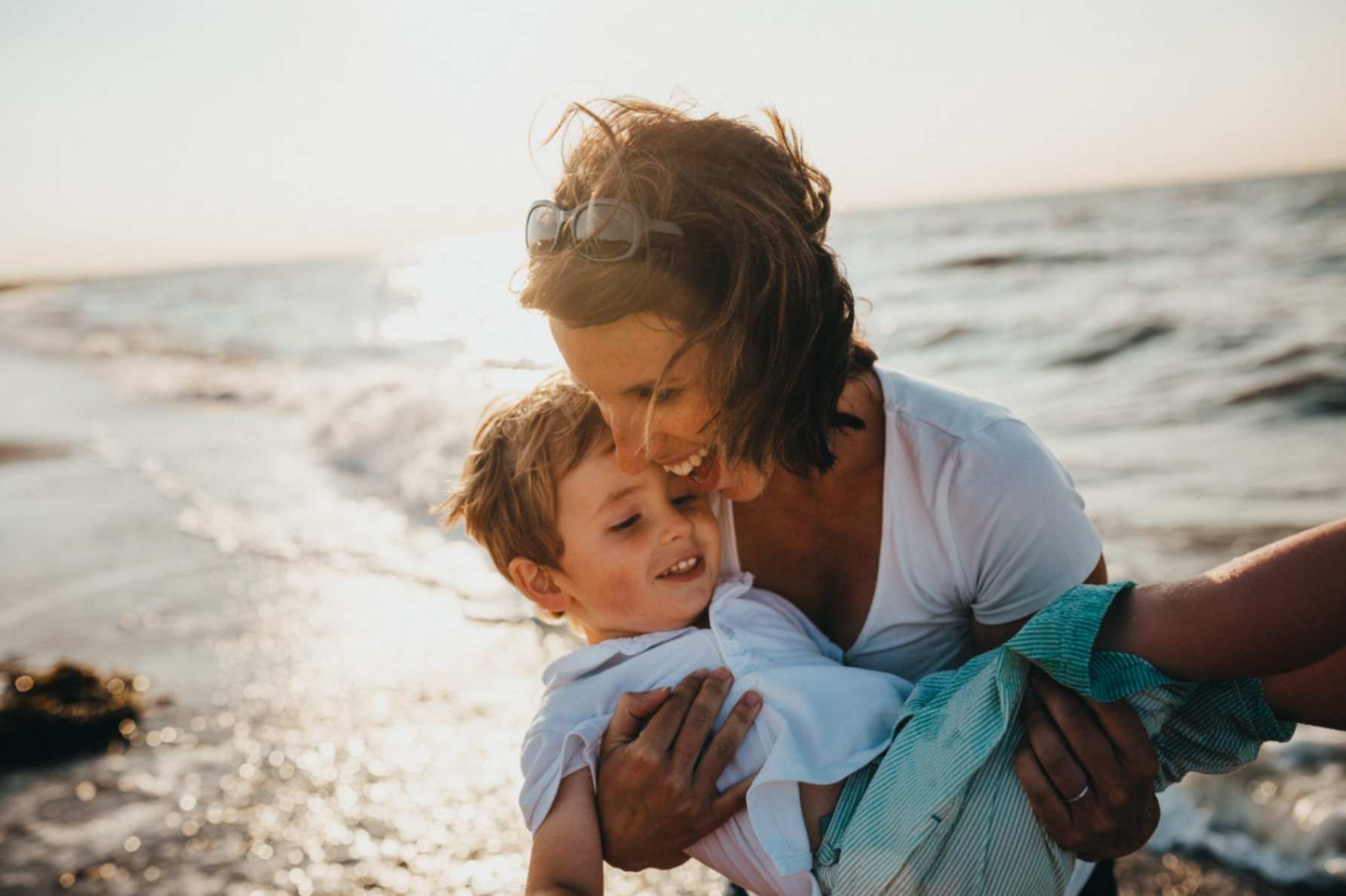 A person holding a child on a beach