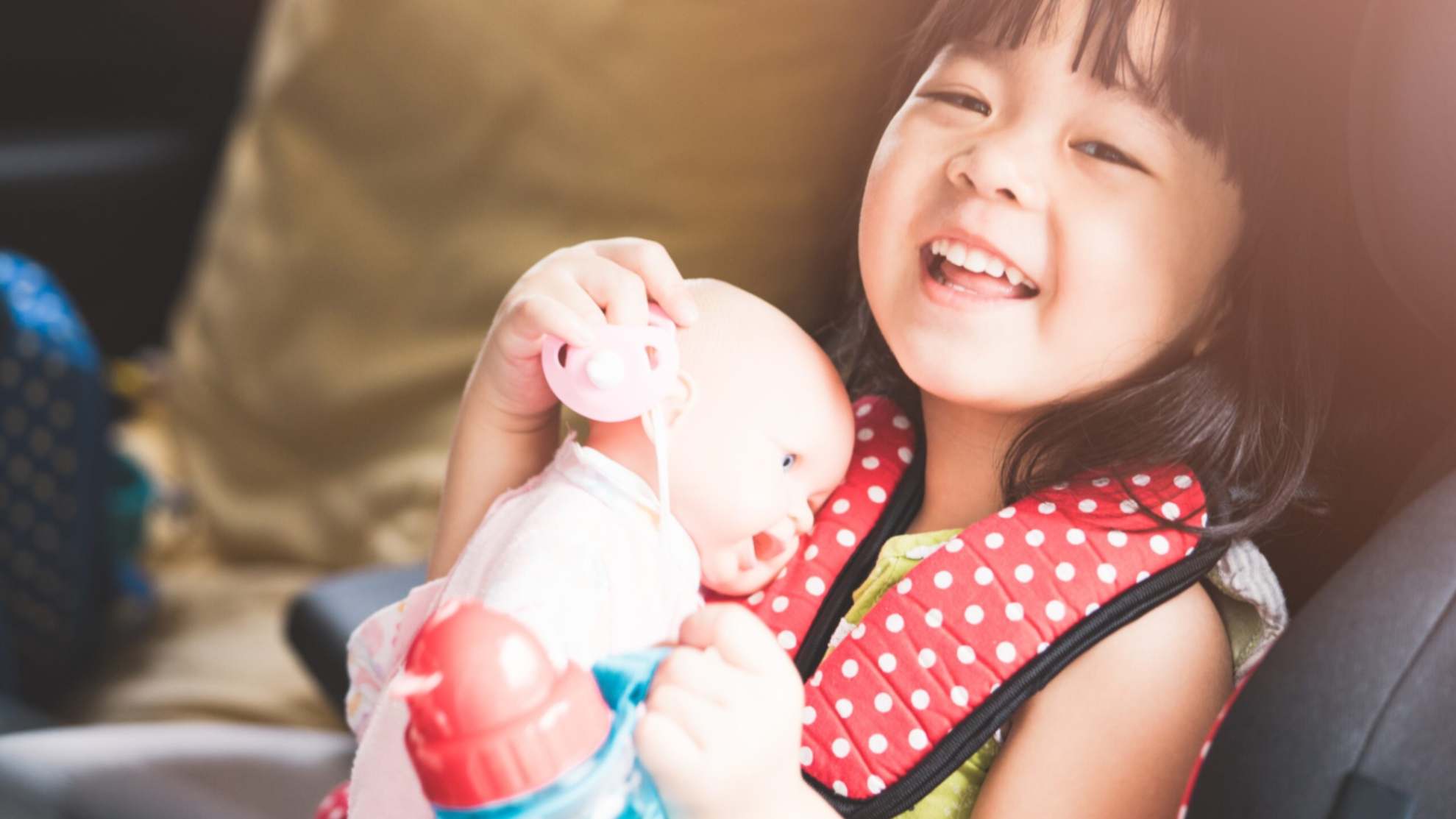 A child in a car seat holding a doll