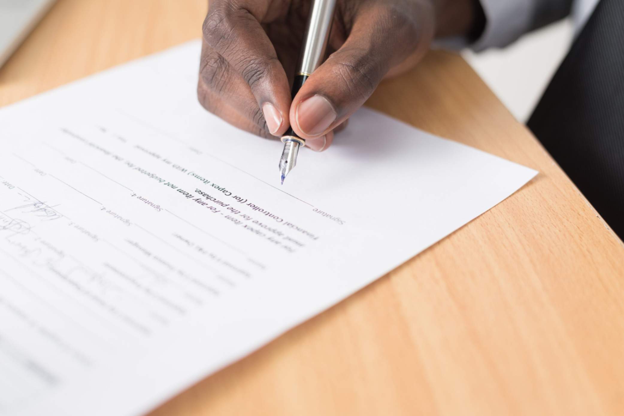 A person signing legal documents with a fountain pen