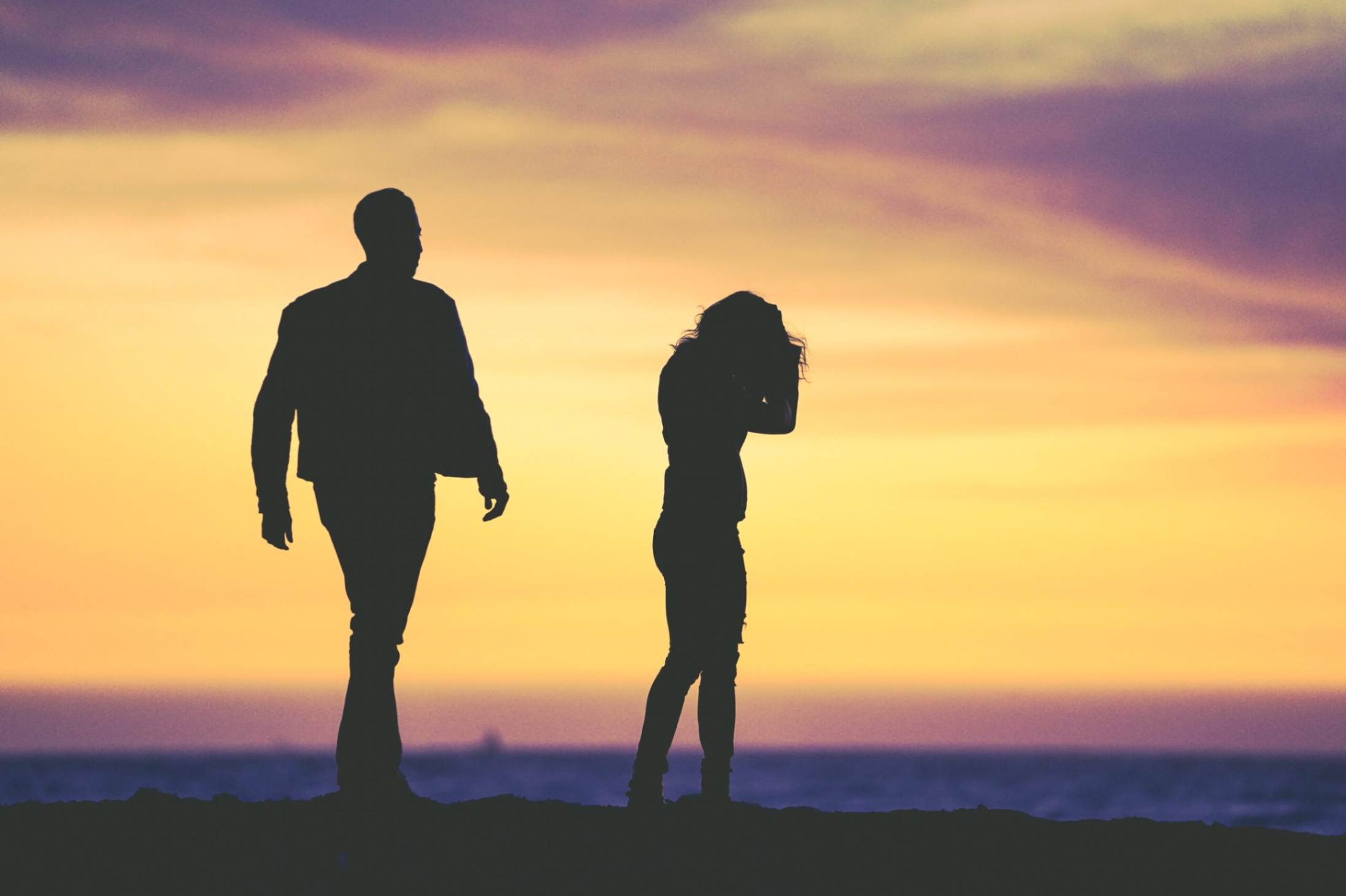 An upset couple photographed against a sunset background