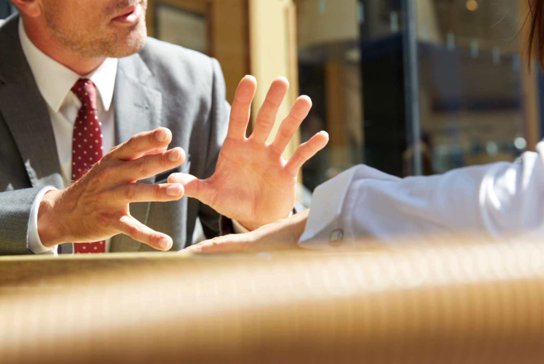 Two people seated at a desk talking to each other